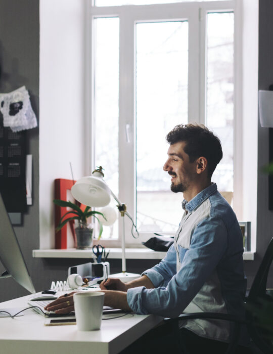Young man working on computer while sitting at his working place in office