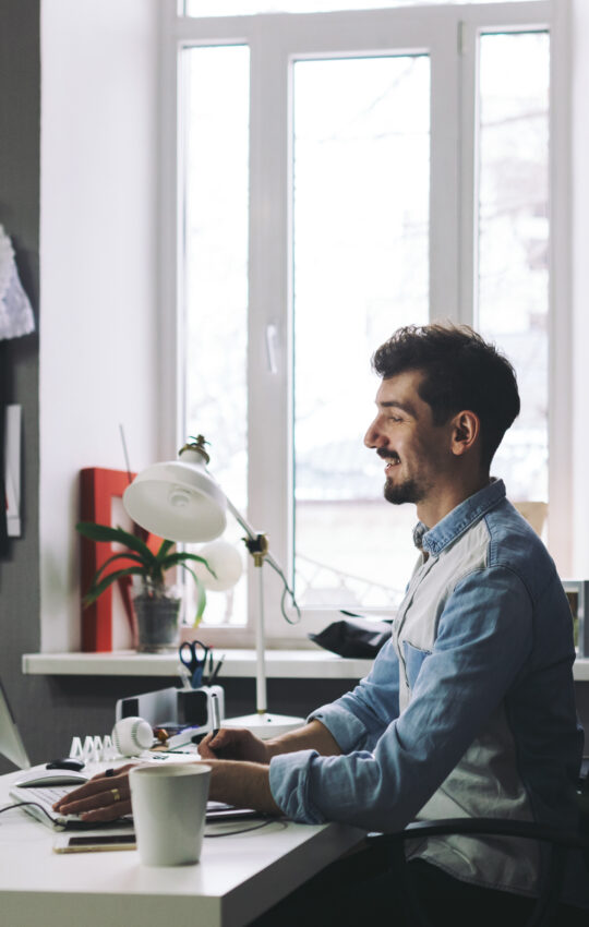 Young man working on computer while sitting at his working place in office
